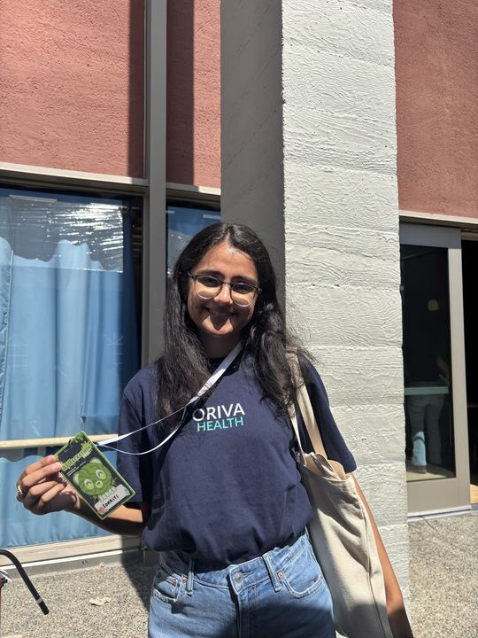 Sukriti in an Oriva Health shirt holding her judge badge at a UC Berkeley hackathon